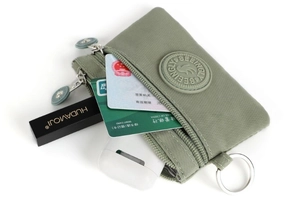 Detailed view of sage green nylon pouch with double zippers and metal key ring storage