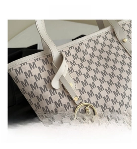 Detailed macro view of monogram print and golden M logo pendant on tote bag