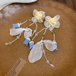 Detail of fabric flower earrings with transparent beads and white ribbon bow accents
