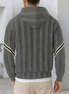 Macro shot of grey cable knit texture on hoodie sleeve with black and beige stripe detail