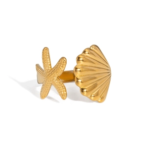 Détail d'une bague réglable dorée avec motif coquillage et étoile de mer sur fond blanc
