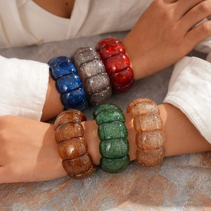 Detailansicht bunter Acrylharz-Armbänder mit Glitzer am Handgelenk des Models