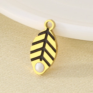 Macro view of gold leaf pendant with black enamel stripes and a white pearl detail