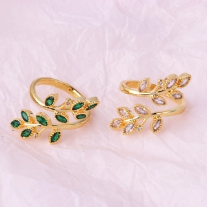 Detail view of gold-plated wheat-ear cross rings with green and white marquise zircons