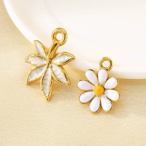 Macro view of 18K gold plated daisy and maple leaf enamel pendants for DIY jewelry