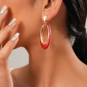 Close-up of a model wearing a gold and red enamel oval drop earring from the six-piece set