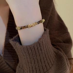 Detail of vintage beaded bracelet with brown tiger eye stones and golden metal accents