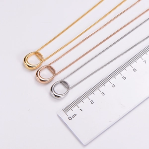Close-up of three minimalist teardrop necklaces in gold, rose gold, and silver finishes