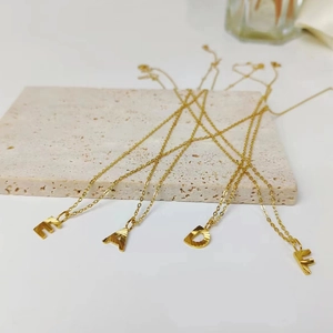Detailed close-up of golden initial necklaces with radial texture on stone surface