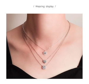 Detailed view of layered silver necklaces with heart, round, and square crystal pendants
