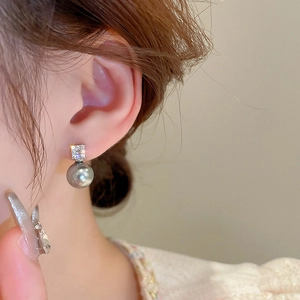 Close-up of model wearing geometric square zircon and dark grey pearl earrings