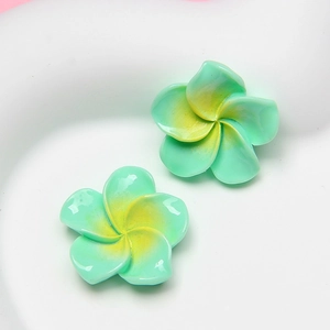 Close-up of green and yellow gradient resin frangipani charms for DIY accessories