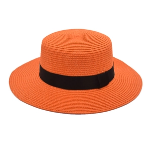 Close-up of orange straw boater hat featuring a woven texture and black grosgrain ribbon