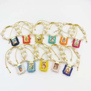 Religious pearl beaded bracelets with various saint icon charms and adjustable cord