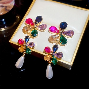 Close-up of gold-plated flower earrings with colorful crystals and teardrop pearls