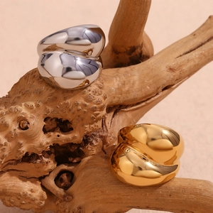 Detail of 18K gold and silver crisscross flower rings on a textured root display