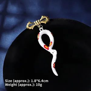 Detail of vintage snake brooch with golden bow and white enamel charm, 1.8x6.4cm