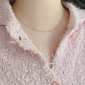 Close-up of a delicate gold square geometric pendant necklace worn on the collarbone