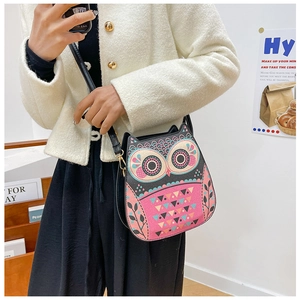 Détail du sac bandoulière au motif hibou coloré porté avec un manteau blanc décontracté