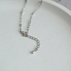 Macro detail of the lobster clasp and adjustable silver chain with minimalist bead