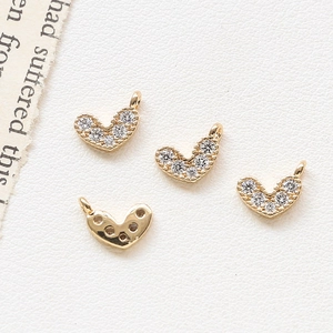 Detailed view of four gold-plated heart charms with zircons for DIY jewelry making