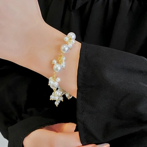 Close-up of elegant pearl bracelet with gold accents on wrist with black background