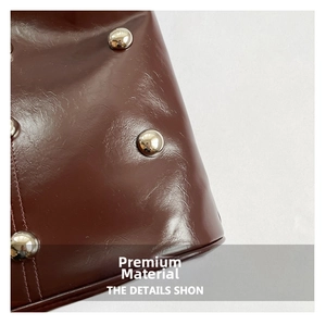 Macro shot of dark brown oil-wax leather texture with silver metal studs and fine stitching