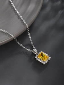 Detailed shot of yellow square gemstone pendant with sparkling halo on silver chain