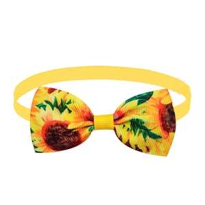 Detail of yellow pet bowtie with vibrant sunflower patterns and ribbed textile texture