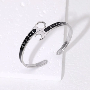 Detailed top view of wrench-shaped silver steel bracelet with black enamel and engraving