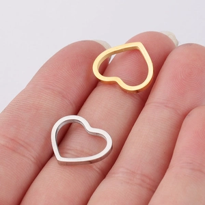 Detailed view of hollow heart pendants in gold and silver finish on fingertips