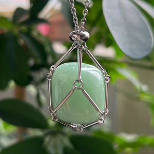 Detail of a green crystal stone pendant in a silver stainless steel mesh net necklace