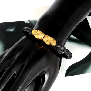 Detailed view of men's black braided leather bracelet with gold skull magnetic clasp