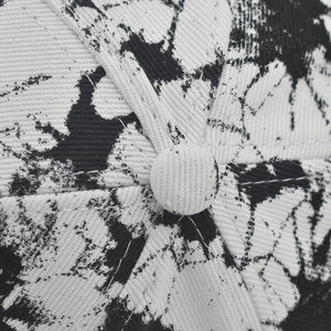 Close-up of tie-dye cotton visor cap showing black and white ink texture and top button detail