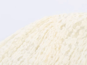 Detailed close-up showing the intricate lace texture and embossed weave of the cream romper