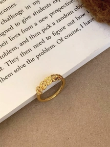 Detail of 24k gold plated ring featuring traditional round copper coin patterns on book