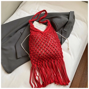 Detail of red handmade woven cotton rope tote bag with long fringe on a gray blazer