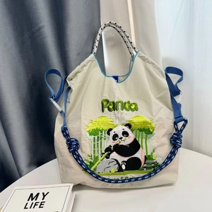 Detail of panda embroidery on cream nylon tote bag with braided blue and white strap