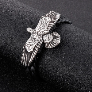 Detailed close-up of vintage eagle charm with intricate textures on black braided leather strap