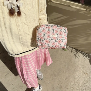 Detail of pink floral quilted makeup bag held by hand featuring soft cotton fabric texture