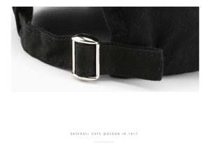Detail view of the adjustable silver metal buckle on the black twill cotton baseball cap