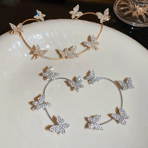 Close-up of sparkling rhinestone butterfly ear cuffs in gold and silver finish
