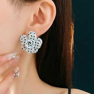 Gros plan de boucles d'oreilles roses à pois noirs et blancs portées par un modèle