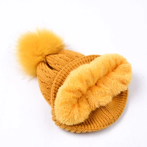 Close-up of winter knit hat with cozy fleece lining and large yellow faux fur pompom