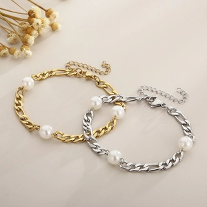 Elegant gold and silver titanium bracelets with pearls and Figaro chain on warm background
