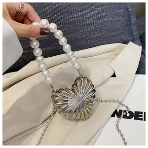 Detailed view of silver heart-shaped shell mini bag with pearl handle and metal ball chain