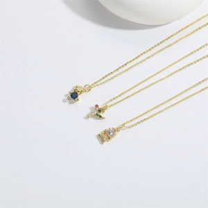 Détail de colliers dorés avec pendentifs ours, lune et pierres précieuses sur fond blanc
