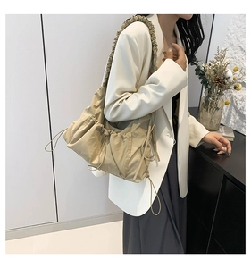 Detail of ruffle shoulder strap and adjustable drawstrings on beige canvas tote bag
