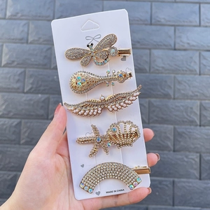 Detailed set of five gold rhinestone and pearl hair clips featuring butterfly and star designs