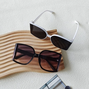 Detail view of large fashion sunglasses with gradient lenses on a wavy wooden stand